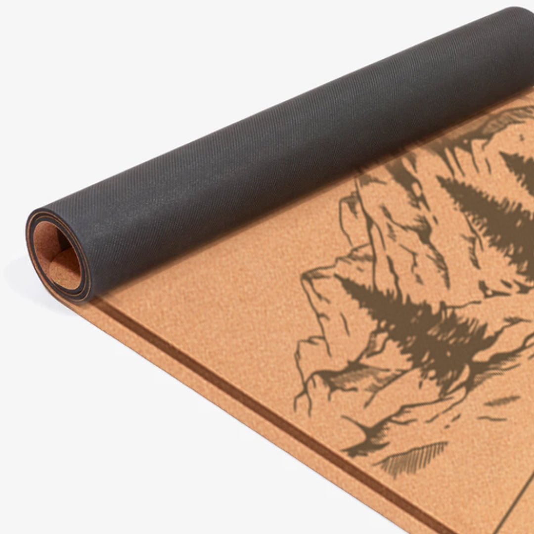 Close-up of rolled eco cork yoga mat with detailed mountain print and black non-slip backing – sustainable fitness accessory.