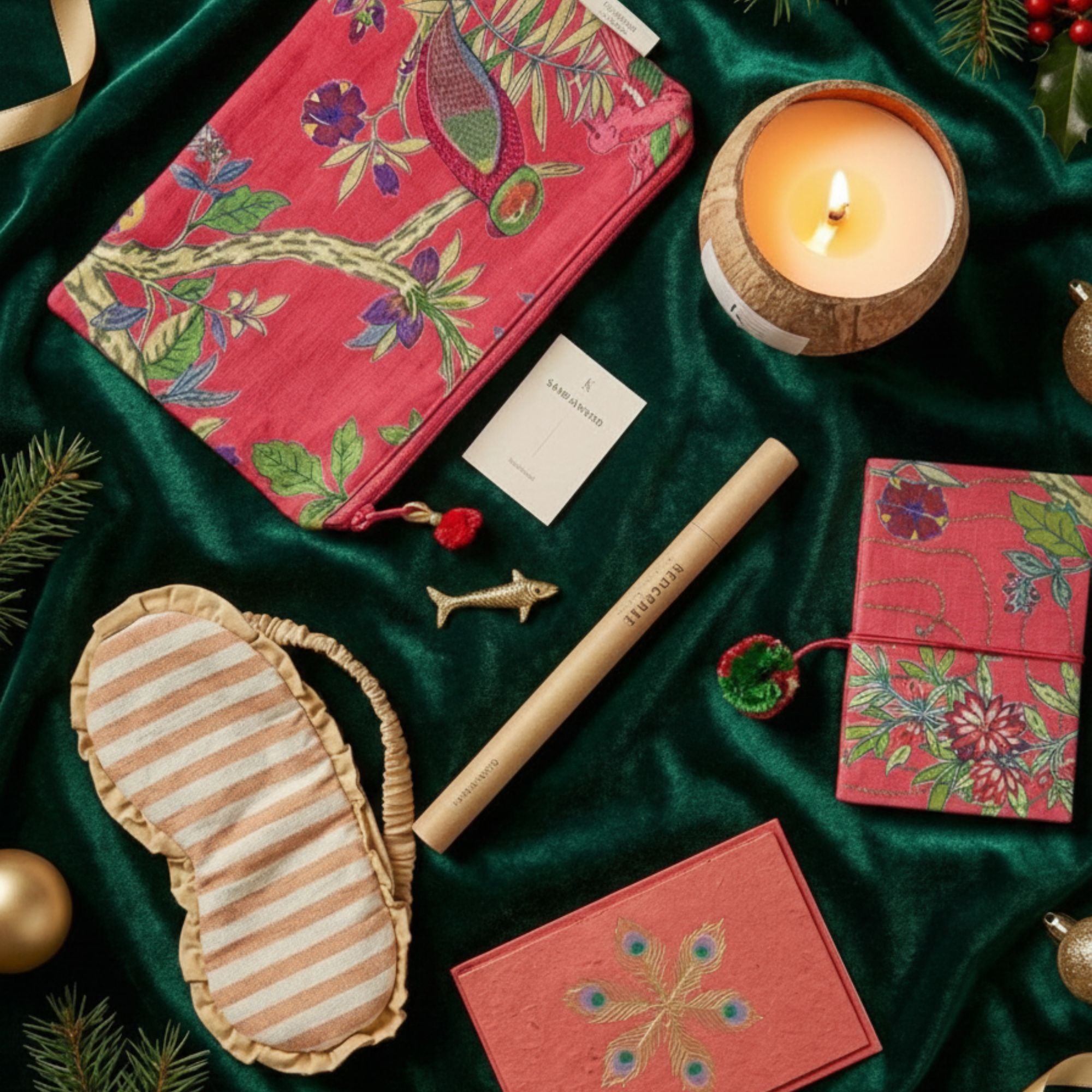 Gift Sets includes notebook, eye mask, and candles on a green fabric background.
