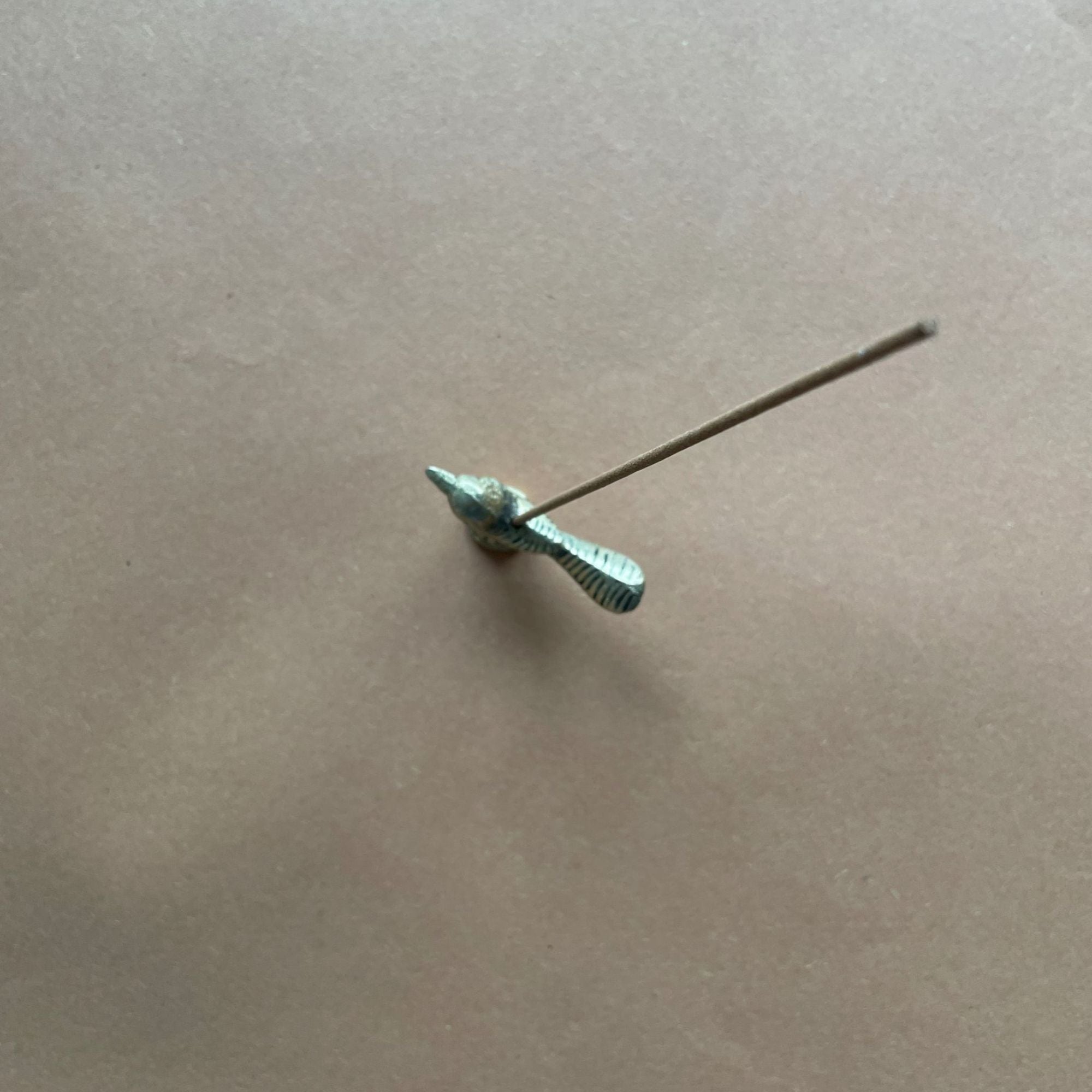 Small fish brass incense holder on a beige surface