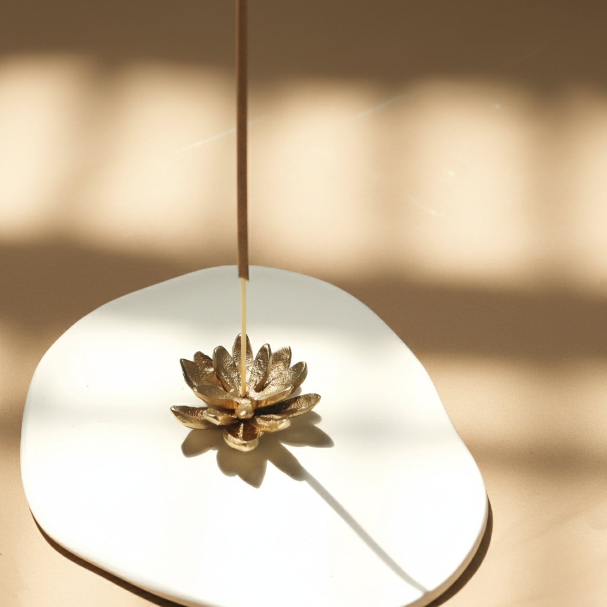 Padma lotus brass holder on white Mykonos ceramic tray—minimal incense set.