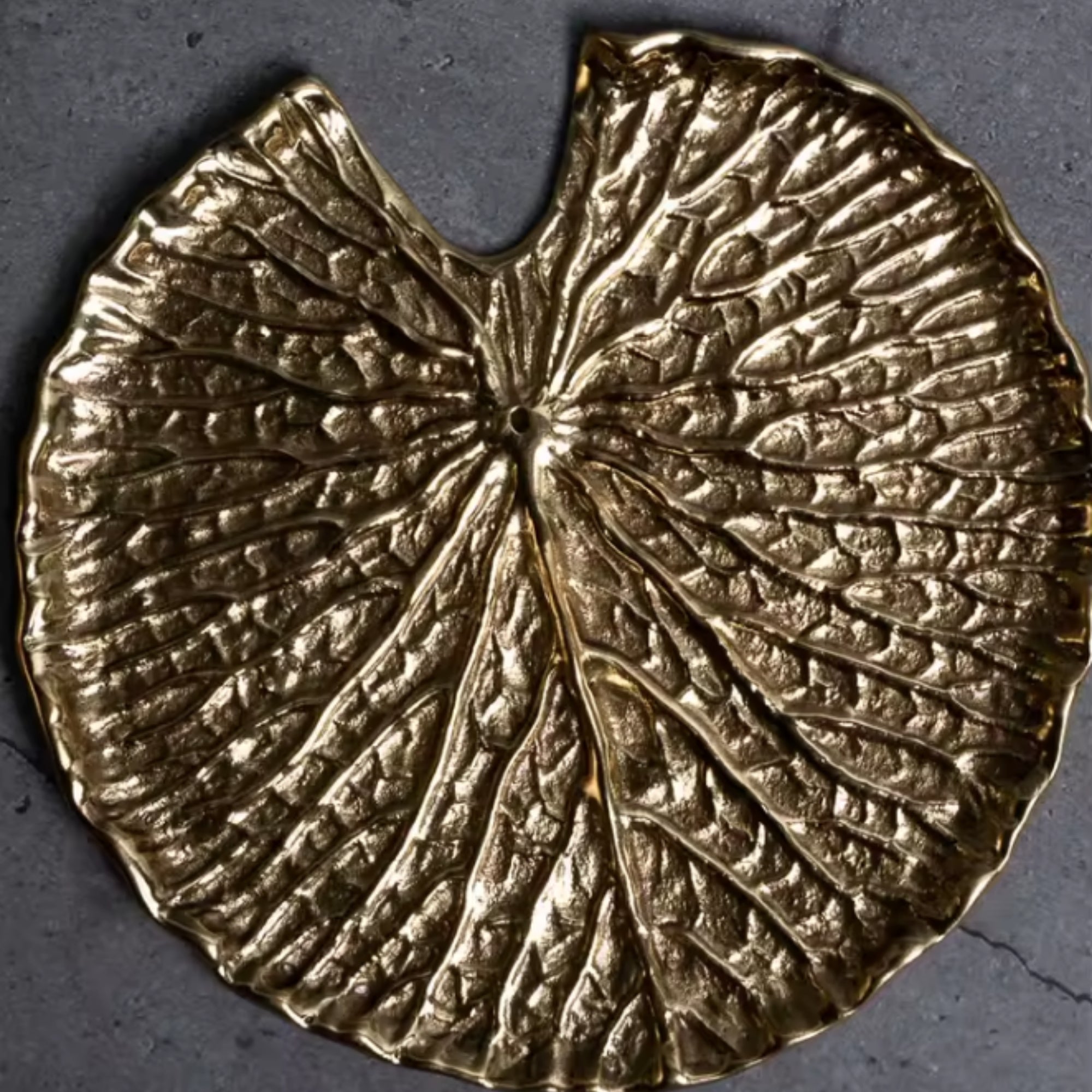 Gold leaf-shaped incense holder on a dark background