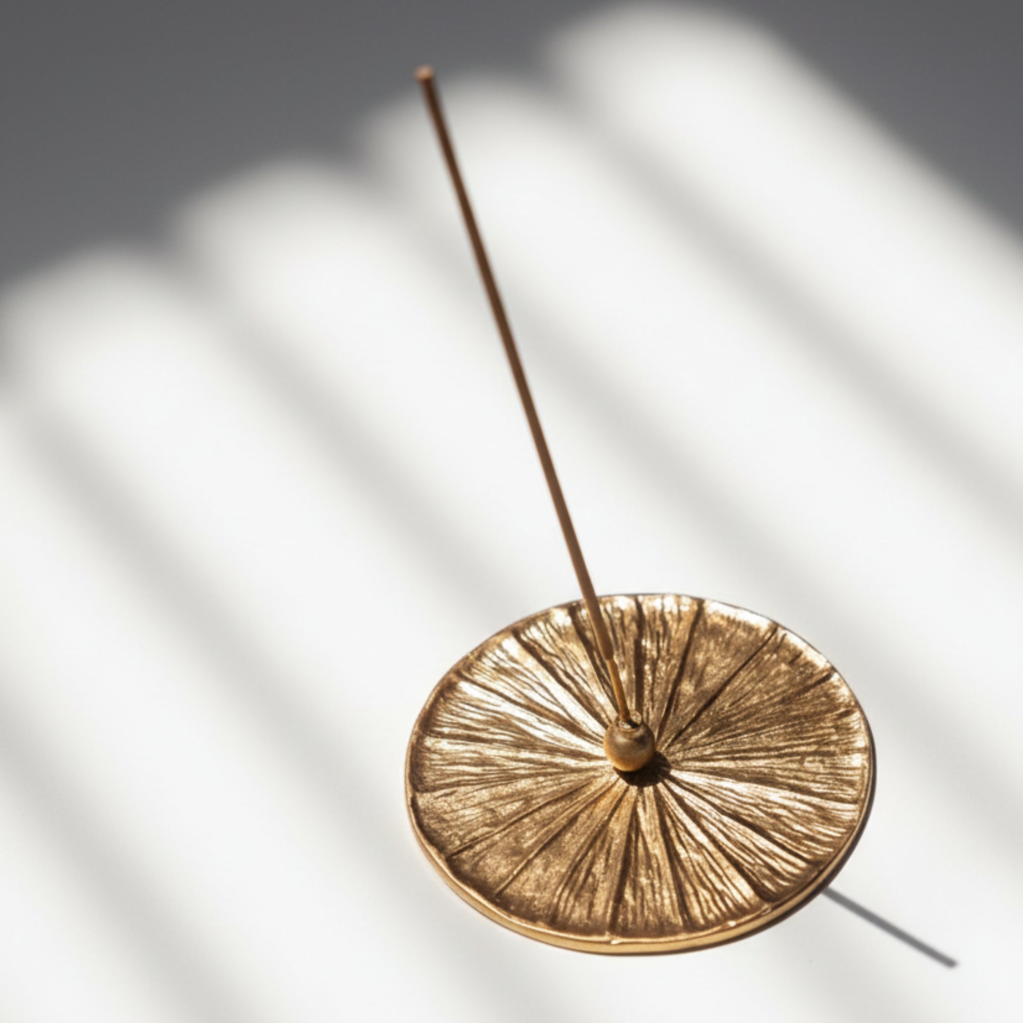 Gold high quality brass handmade incense burner with a single incense stick on a light background