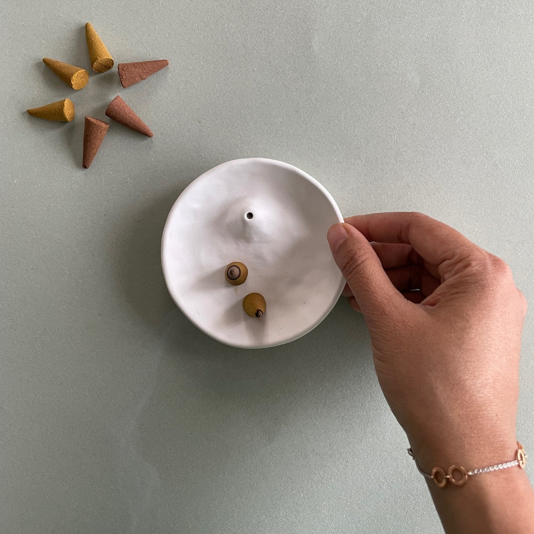 Incense cone shown burnt on an incense holder and palo santo burner