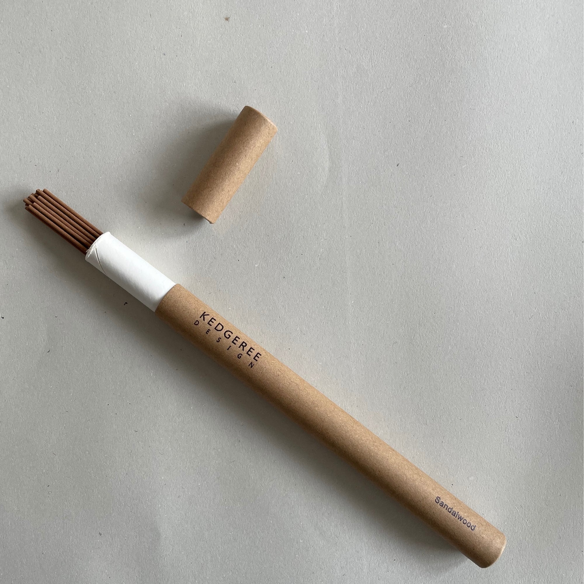 Handrolled natural Kedgeree Design sandalwood fragrance incense holder placed against a light grey backdrop