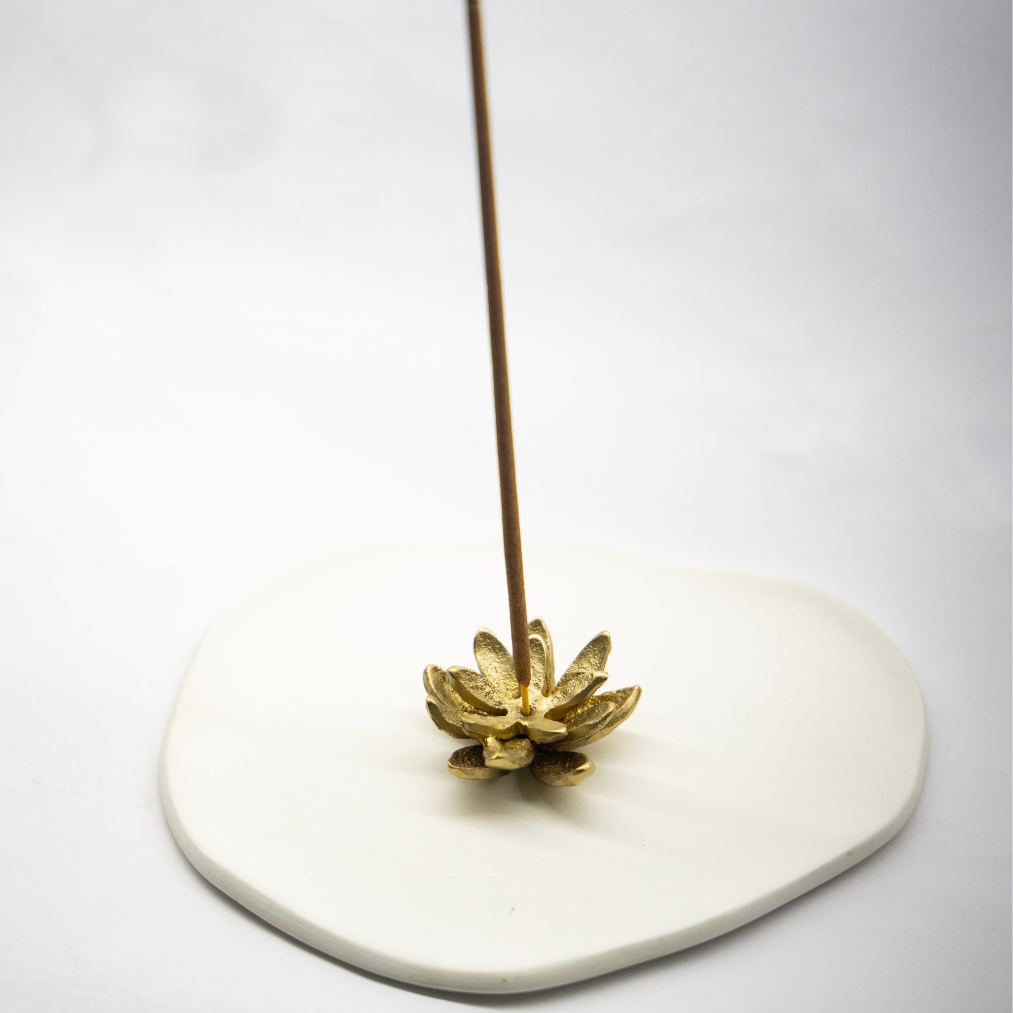 Incense stick on a lotus shaped decorative holder with a white background