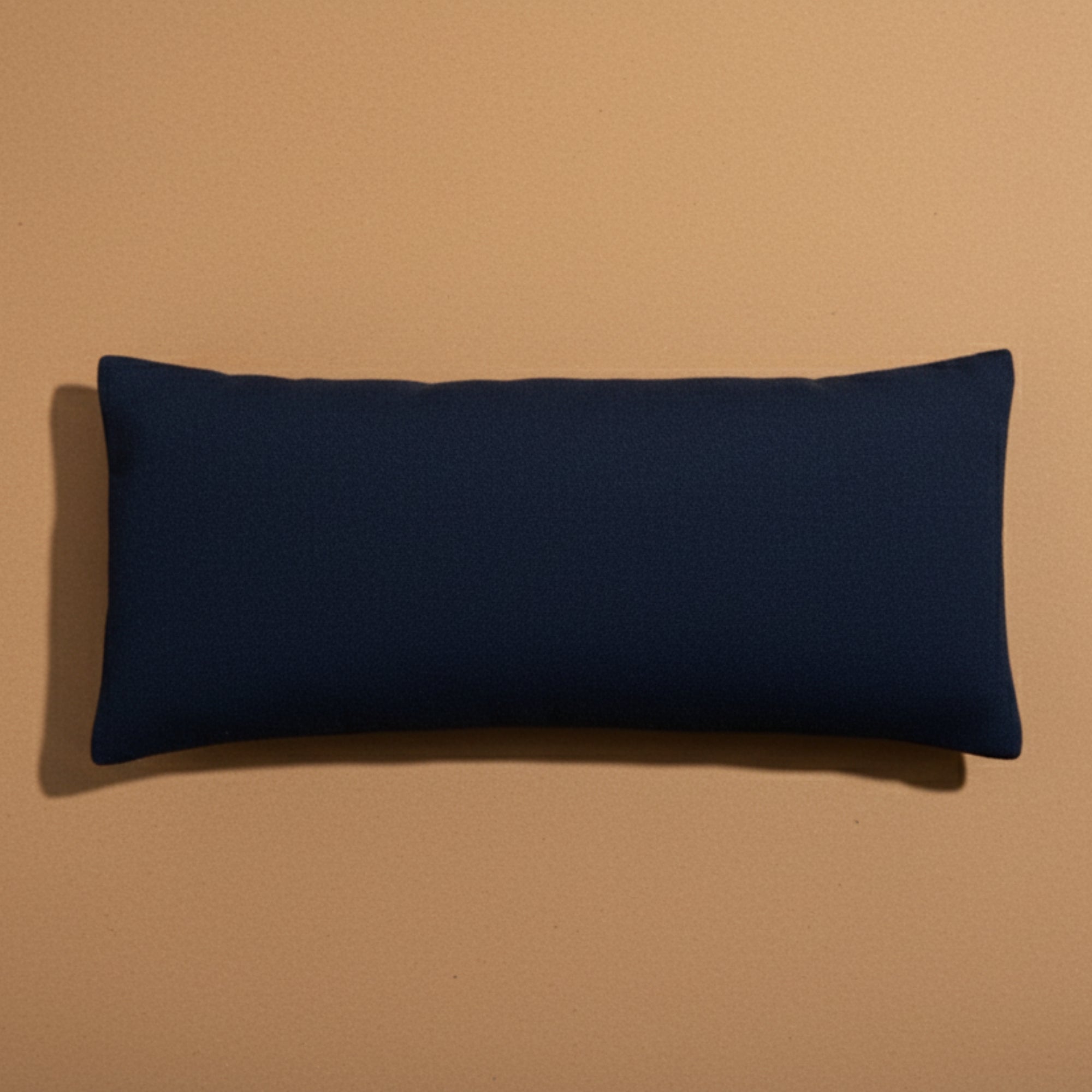 Navy blue rectangular yoga and meditation eye pillow on a beige background