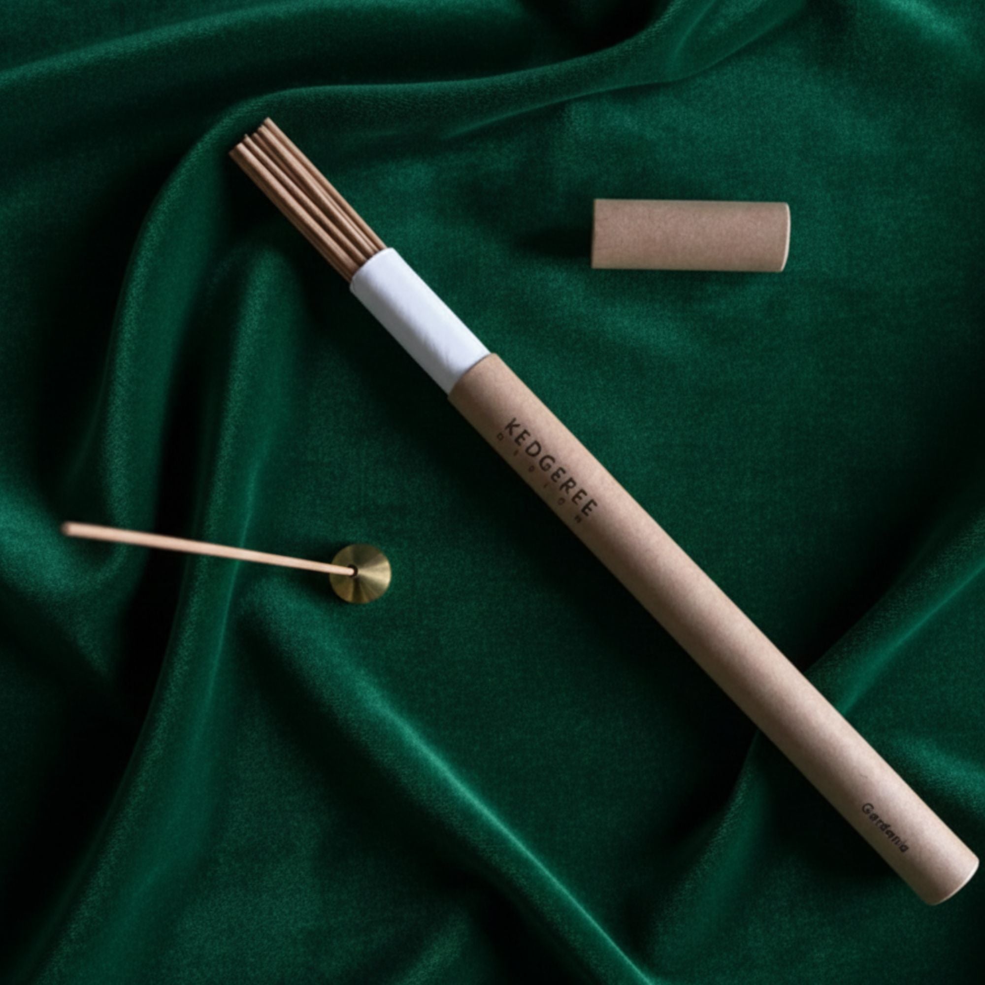 Handrolled incense sticks with holder displayed against a green backdrop
