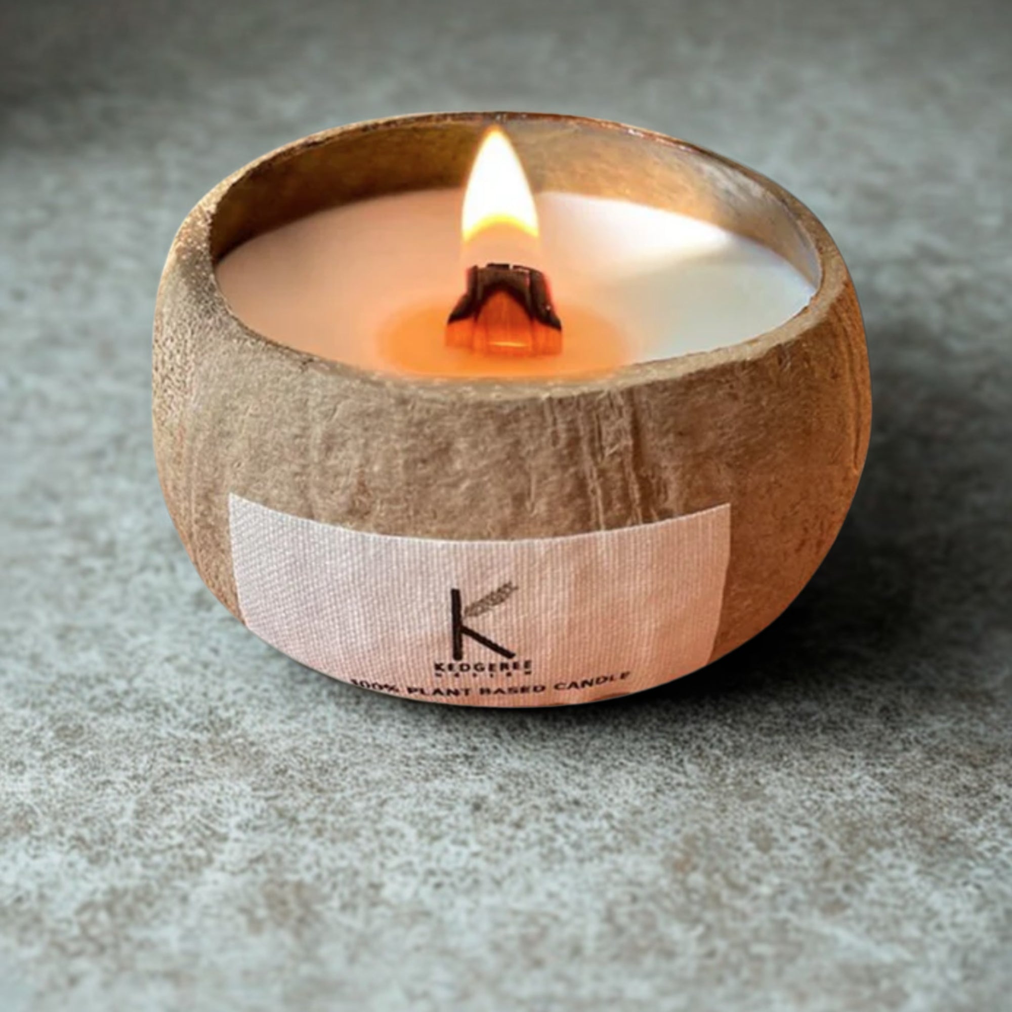 Plant based Candle in a coconut shell with a visible brand label Kedgeree Design on a gray surface