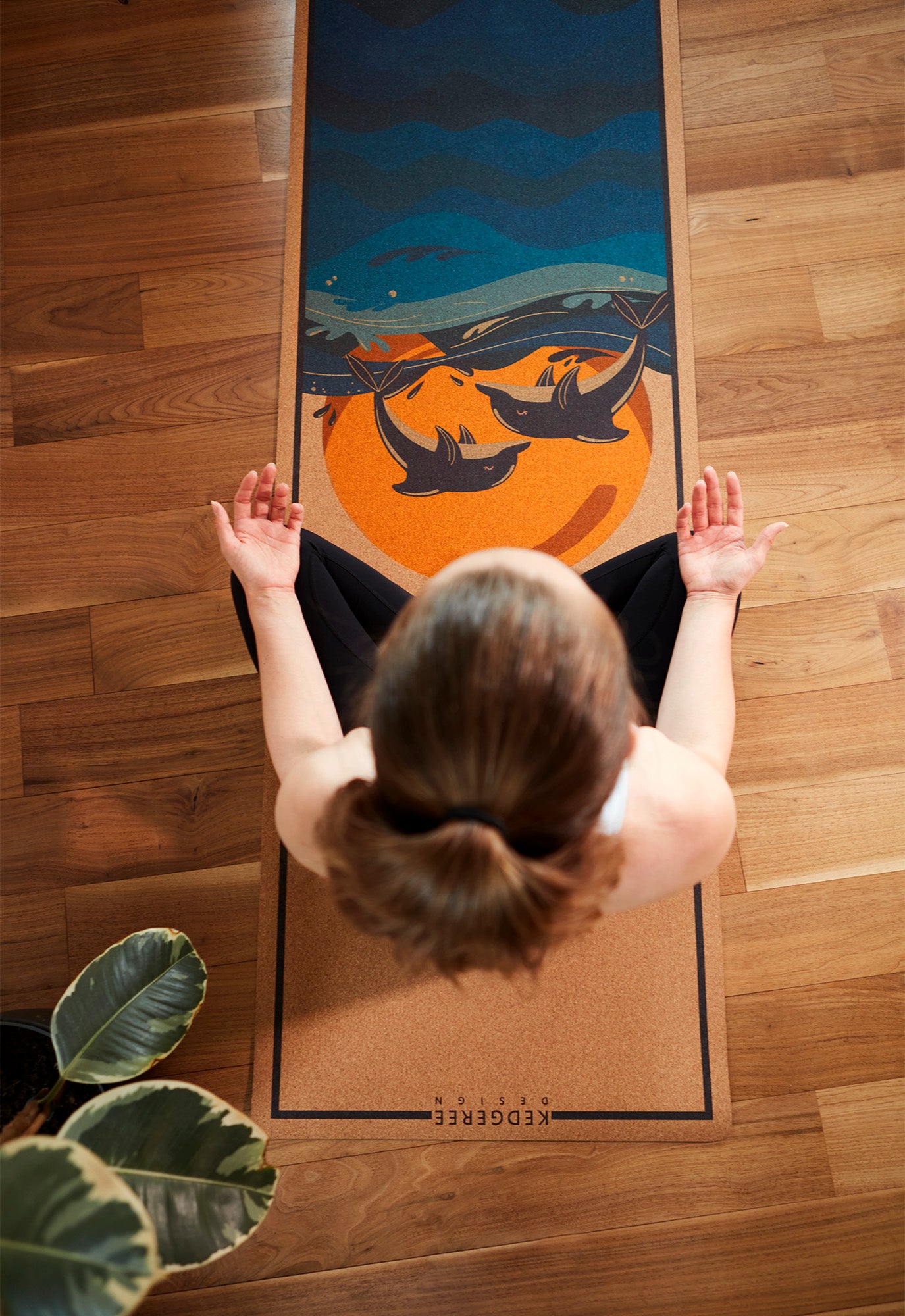 Woman practicing meditation on cork yoga mat with dolphin and sunset ocean artwork – sustainable and stylish yoga mat for daily practice.