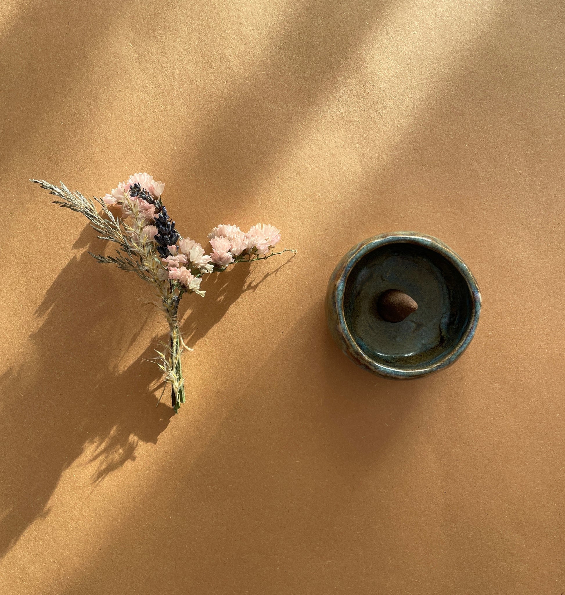 A selection of brown incense cones next to a blue ceramic burner, all placed on a brown surface.