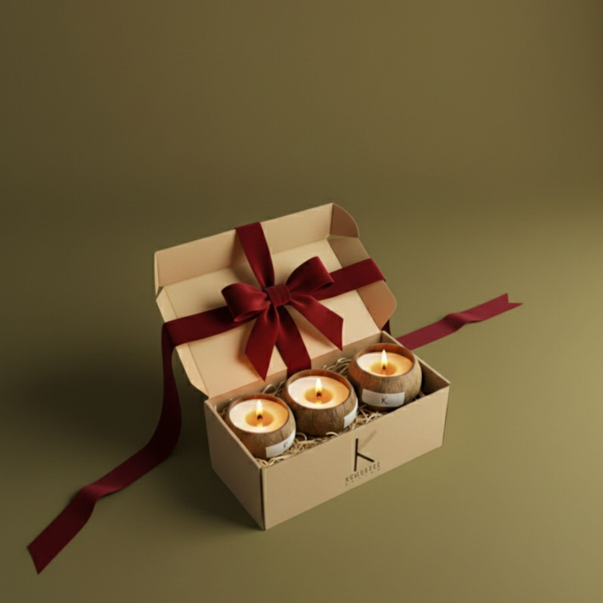 Open christmas eco luxury gift box with natural plant based candles set of 3 and a red ribbon on a green background