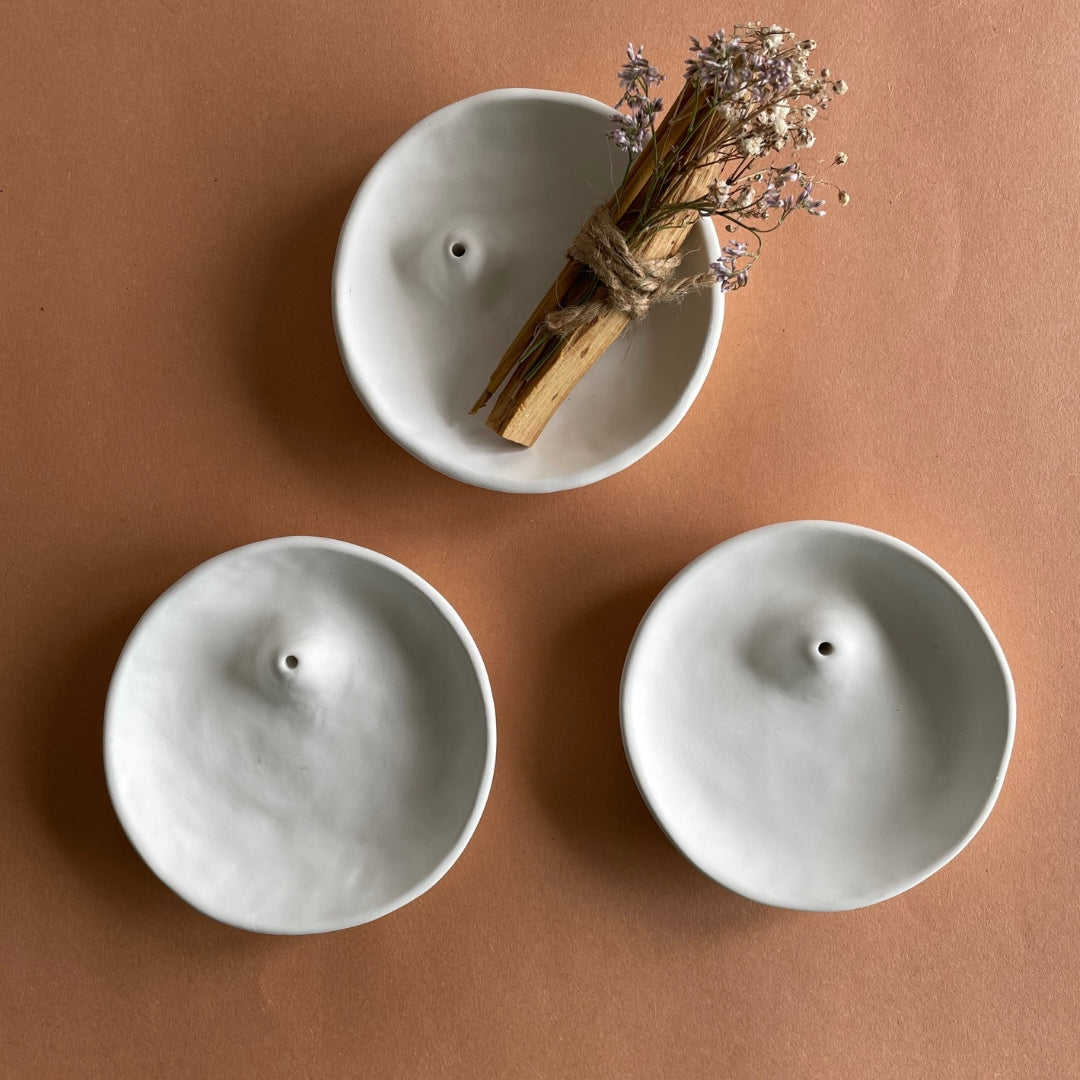 A set of 3 handmade white incense holder and palo santo burner against a dark backdrop