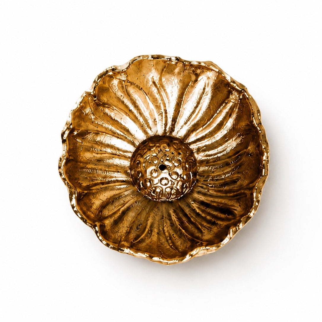 A brass gold lotus flower-shaped incense holder textured center and scalloped petals, photographed from directly above on a white background.