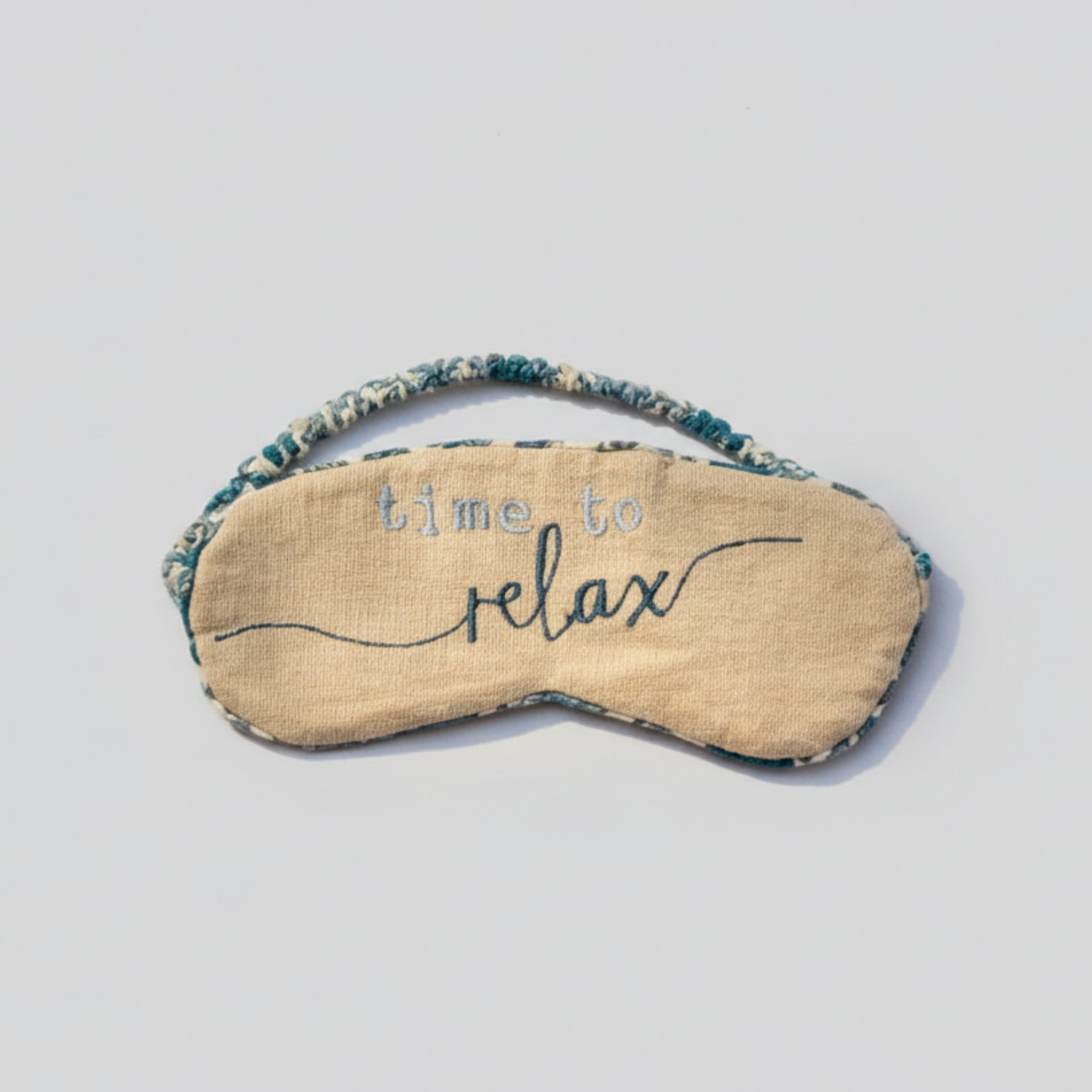 Sleep calming eye mask filled with lavender seeds with 'time to relax' text on a light gray background