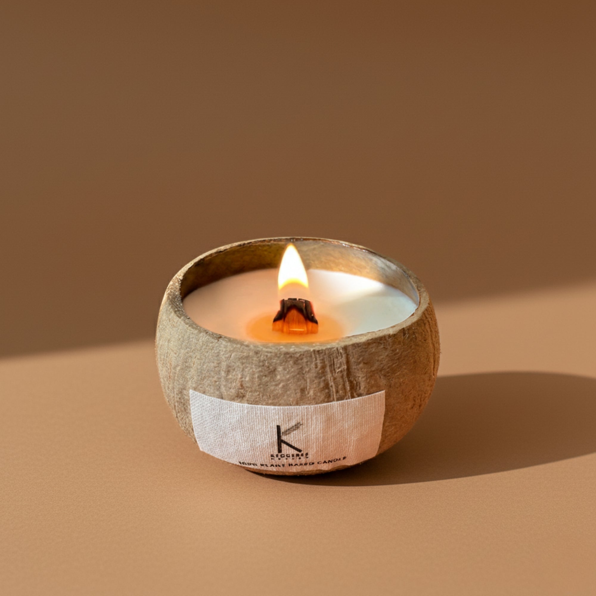 Plant based Candle in a coconut shell with a visible brand label on a brown background