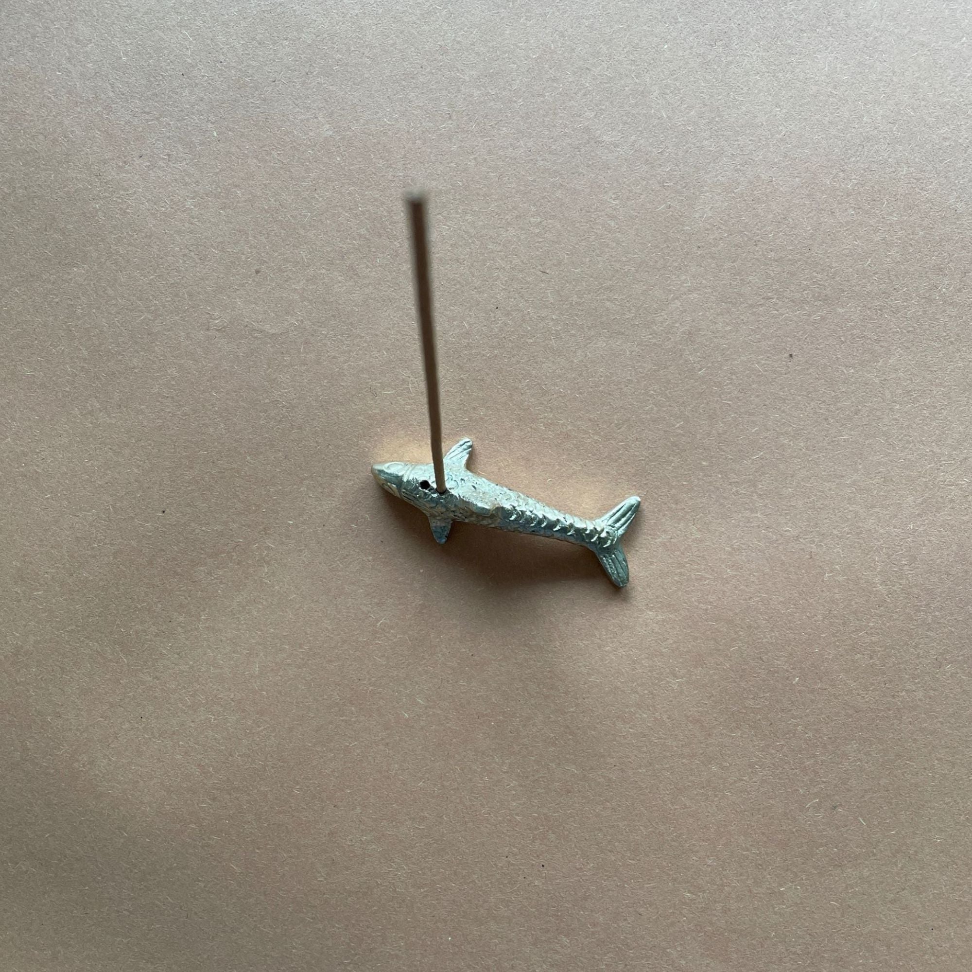 Small shark brass holder on a beige background