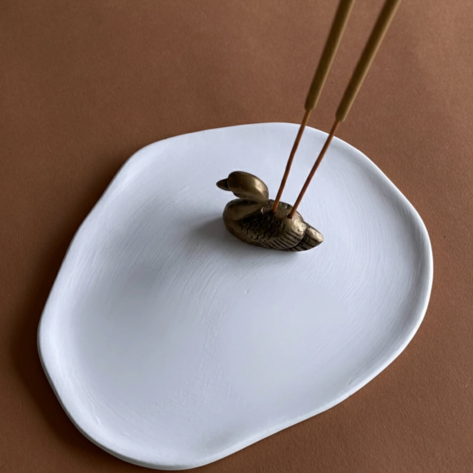 Ceramic ash-catcher tray with brass swan incense holder.