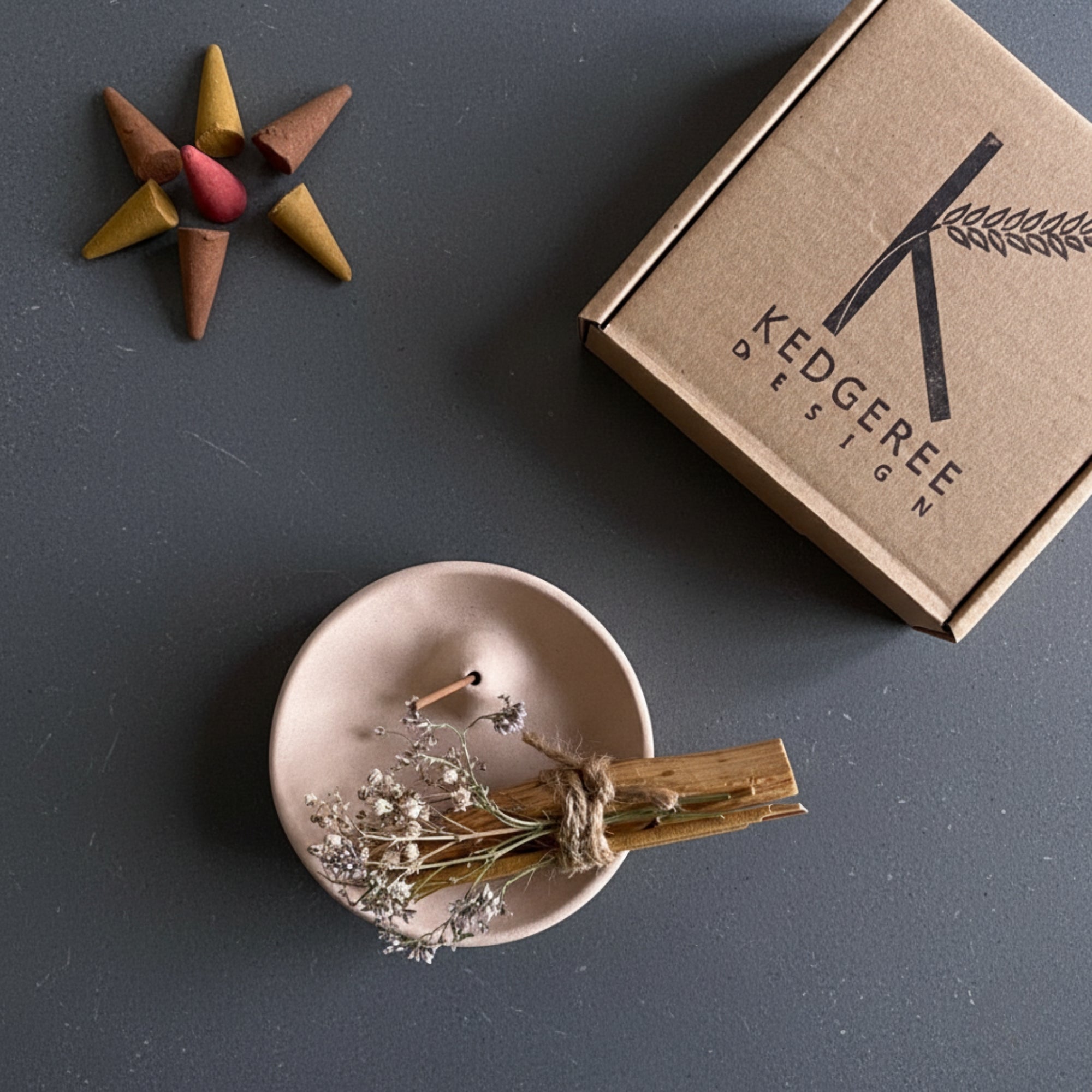 Beautiful Incense holder and palo santo burner, incense cone, and a Kedgeree Design box on a dark surface.