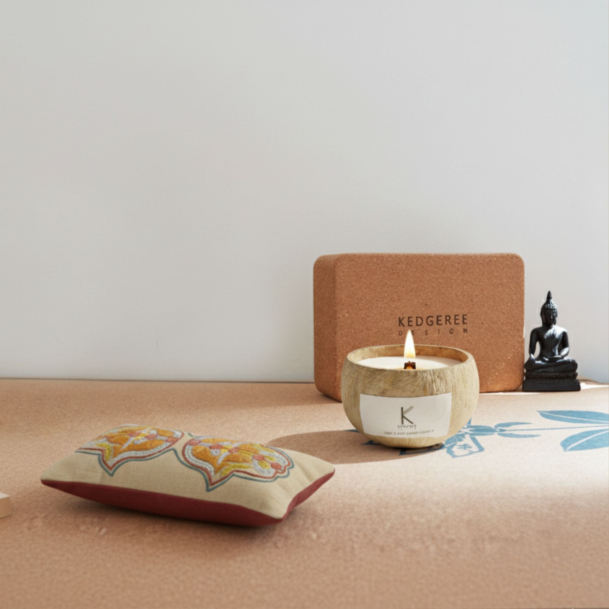 Plant based coconut shell Candle with a lit flame, decorative eye  pillow, and Buddha statue on a surface with a neutral background