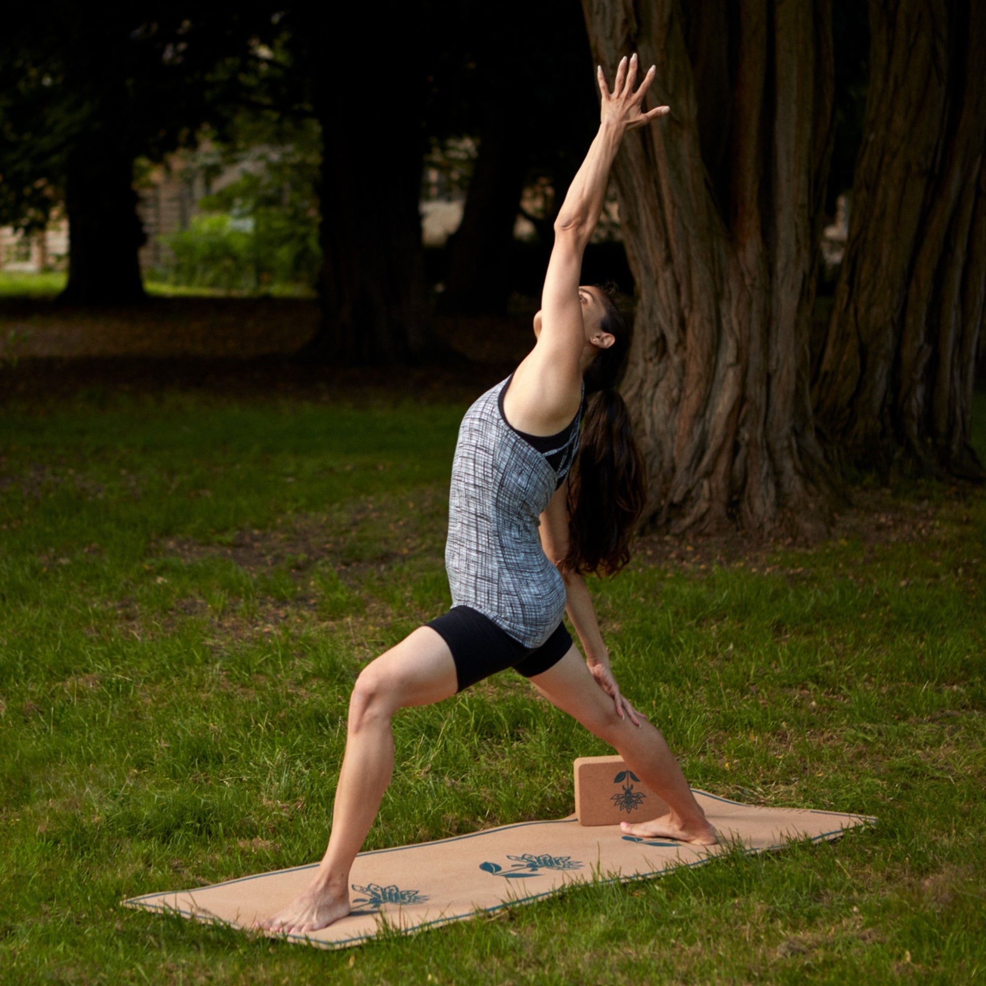 Person practicing yoga on a cork yoga mat outdoors with trees in the background