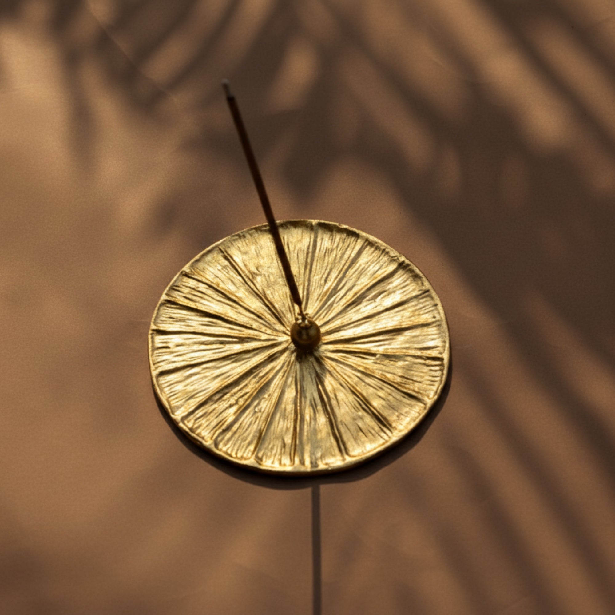 Gold incense high quality brass handmade burner with a single incense stick on a blurred brown background