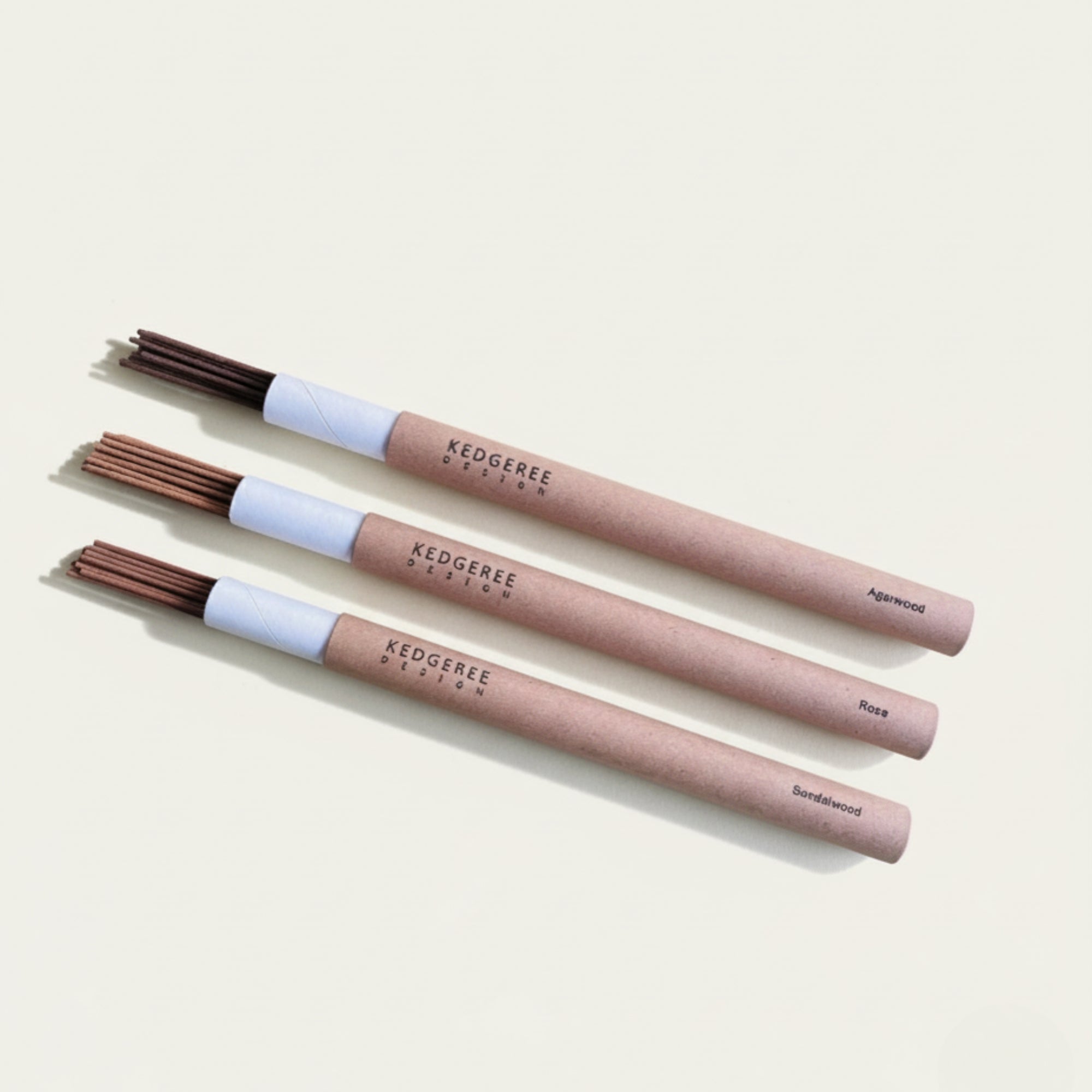 A set of three natural hand-rolled incense sticks tube with three different fragrances such as agarwood, rose and sandalwood displayed against a white background.