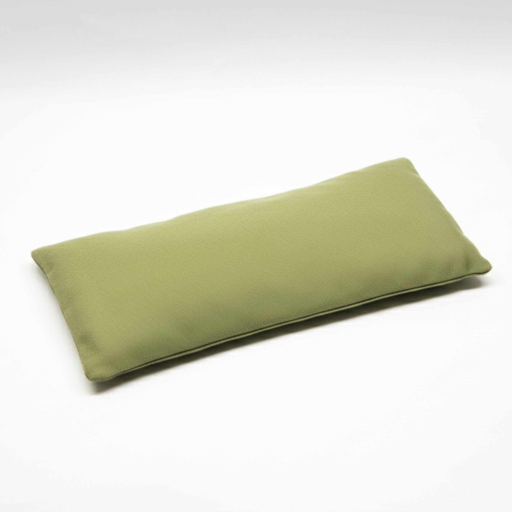 Green rectangular yoga eye pillow filled with flaxseed and lavender seeds on a white background