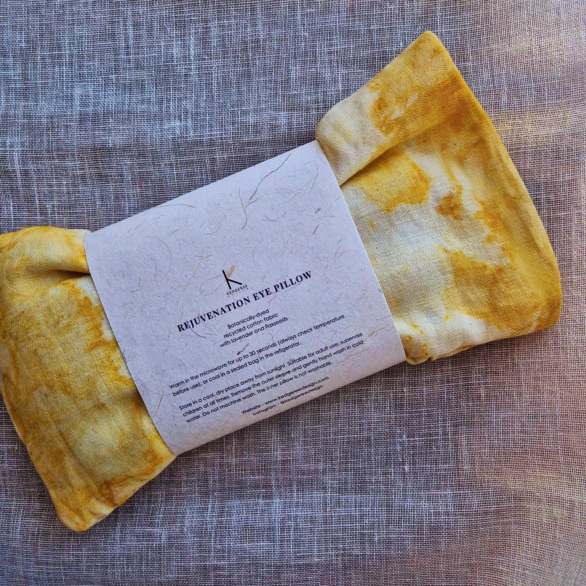 Yellow marigold dyed handmade eye pillow with a label on a textured fabric background