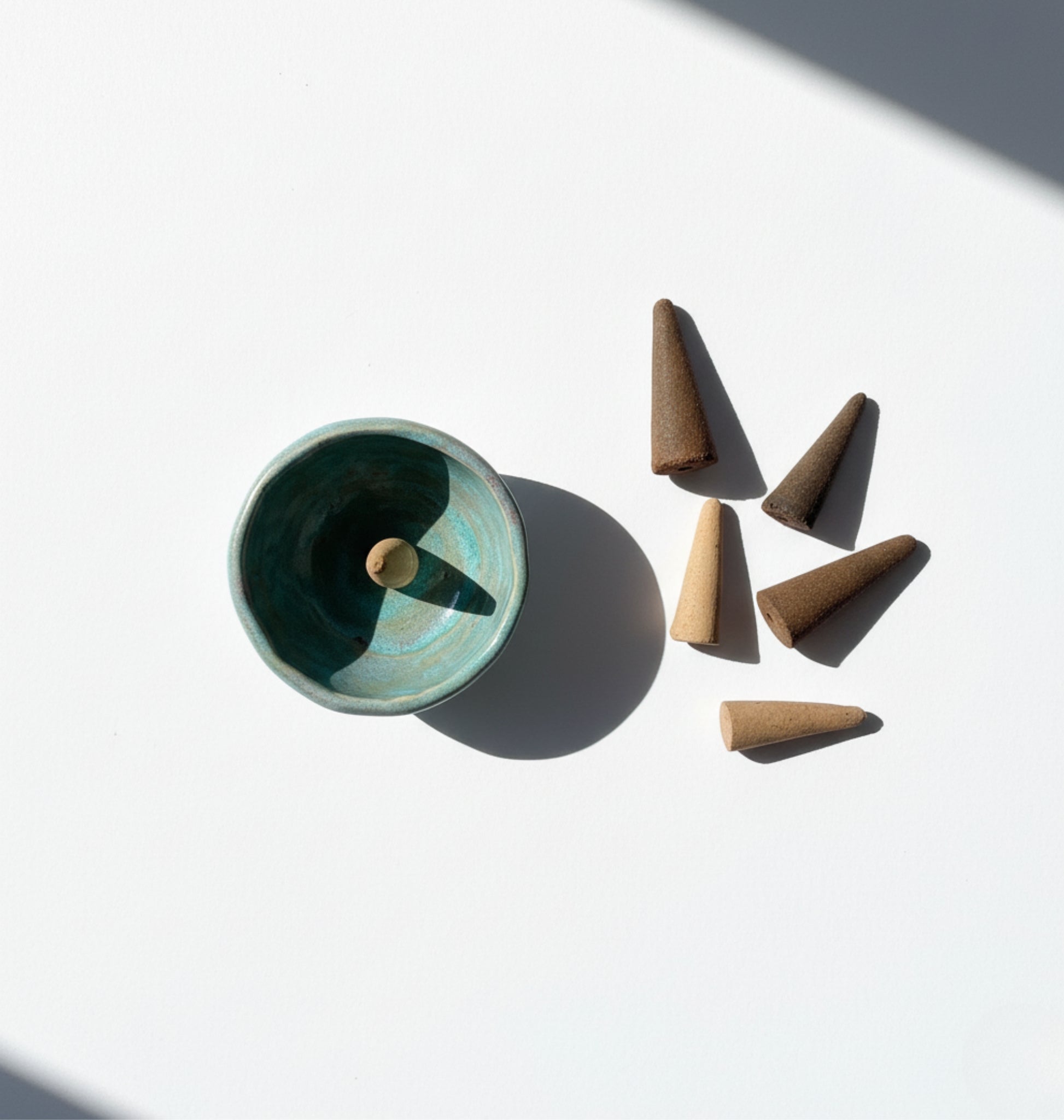 Ceramic burner with incense cones and four incense cones as a display on a white background