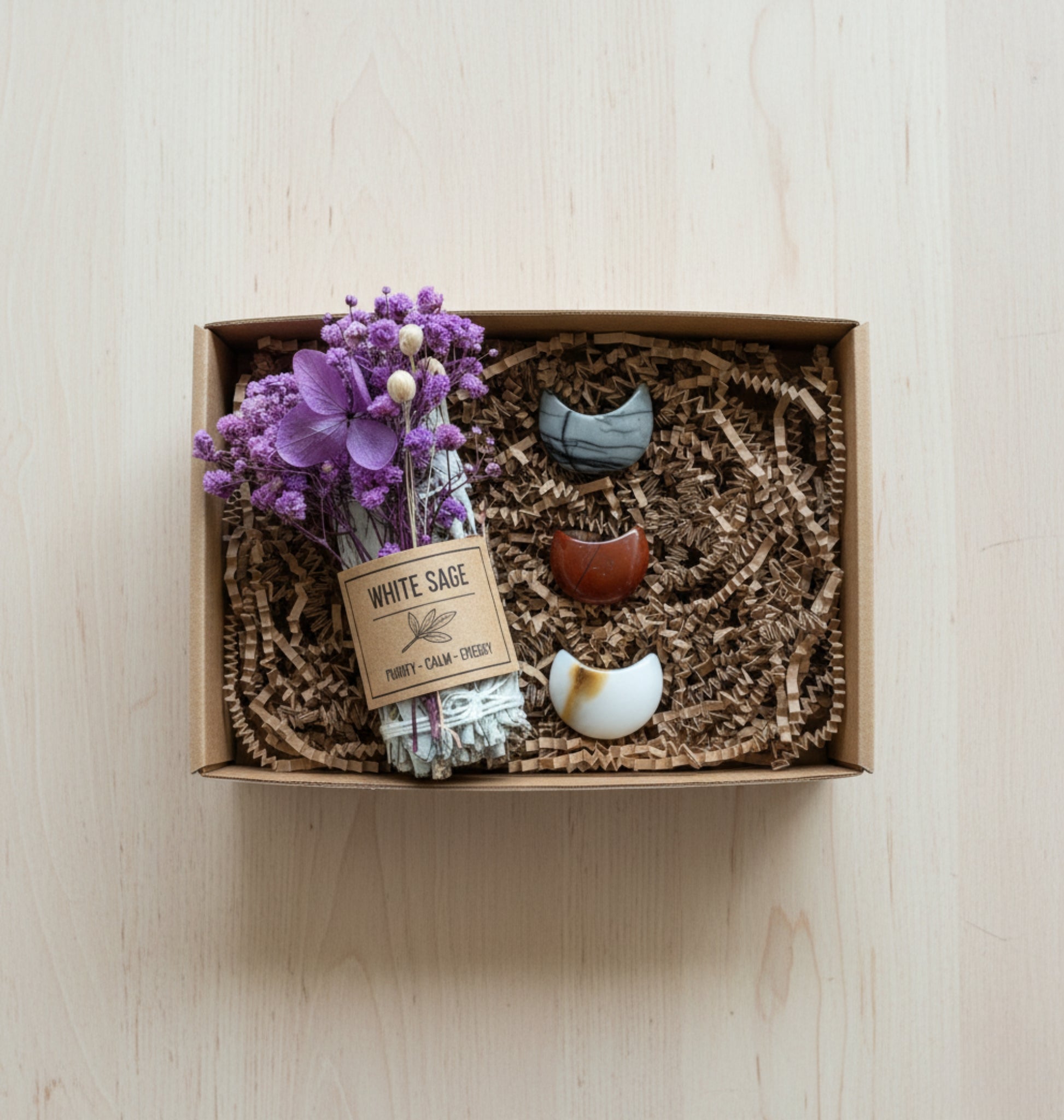 Gift Box with white sage, purple flowers, and decorative items on a wooden surface