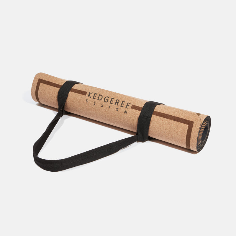 Cork yoga mat rolled up and secured with strap.