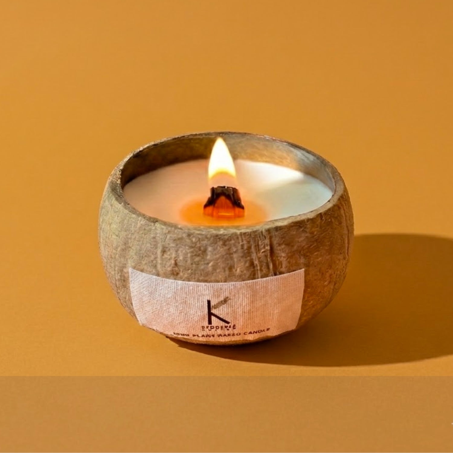 Plant based handpoured Candle in a coconut shell with a visible Kedgeree brand label on an orange background