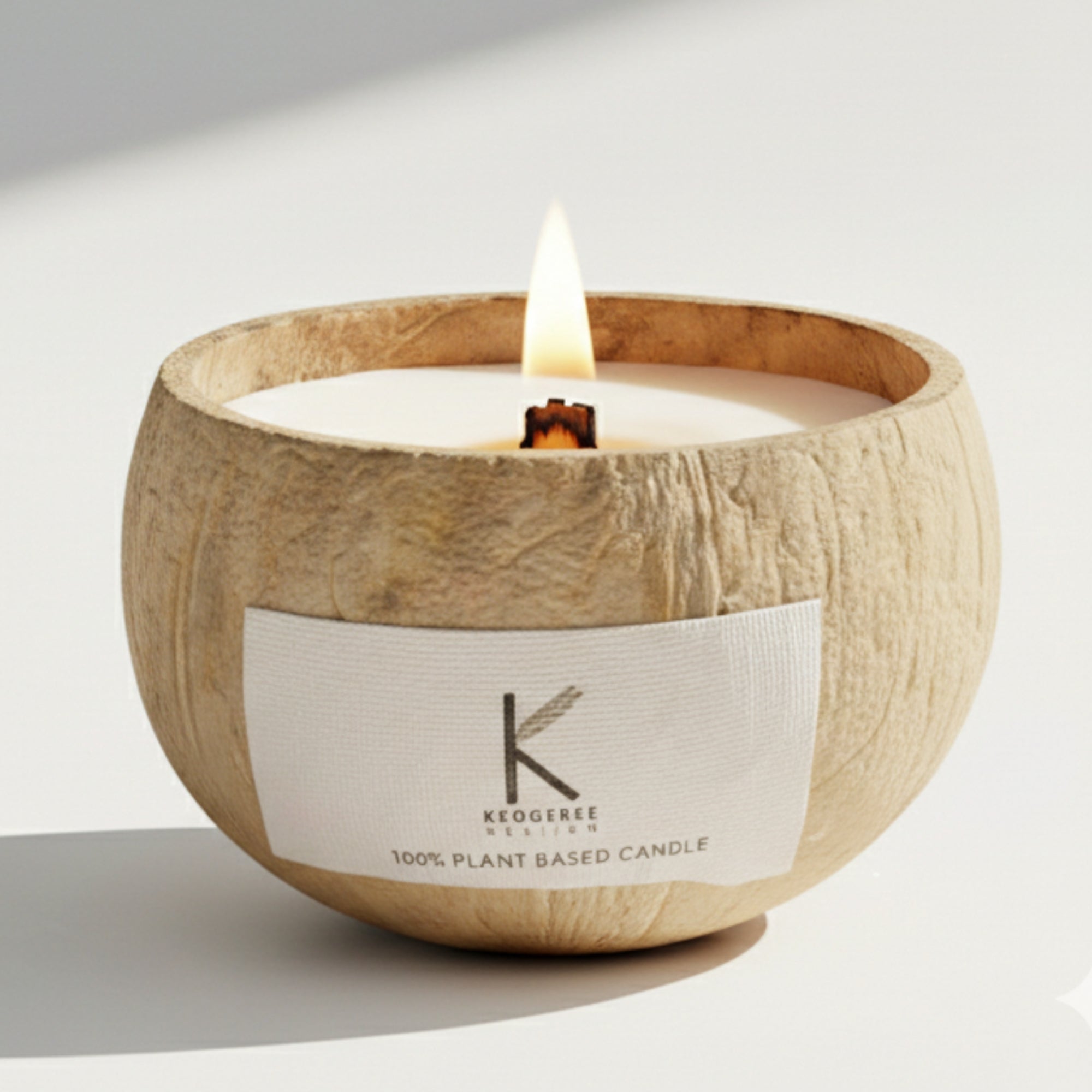 Plant-based Candle lit in a coconut shell holder with a visible brand label on a light background